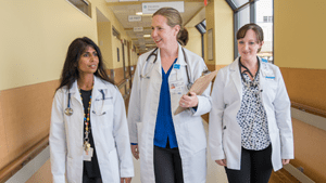 Three female doctors walk down a hallway while having a conversation