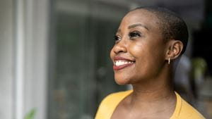 A Black woman smiles out a window