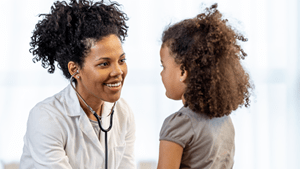 A Black pediatrician meets with a young Black girl