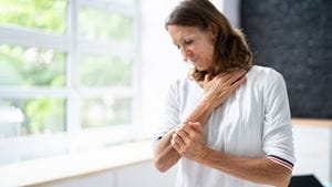 A White woman itches at a patch of shingles rash on her arm