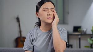 Asian woman was sick with eyes pain, irritate itching her eyes, sitting on sofa in living room at home
