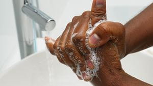 Black person washing their hands with soap and water