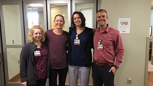 Three doctors and a patient smile outside a cancer treatment center