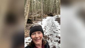 Jolene takes a selfie on a trail run in the woods with slush on the pathway