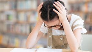 girl holding her head while studying