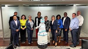 A group of hospital administrators and leadership stands next to a blue and white robot