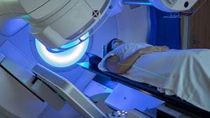 A patient in a gown lies on a table as a radiation therapy machine moves around her