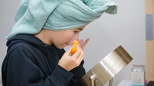 Teenage girl cleaning her face in front of mirror while wearing a towel on head after washing her hair