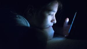 Teenager sending email from smart phone in her bed, Typing text message on smartphone. young cell phone addict teen awake at night in bed using smartphone for chatting