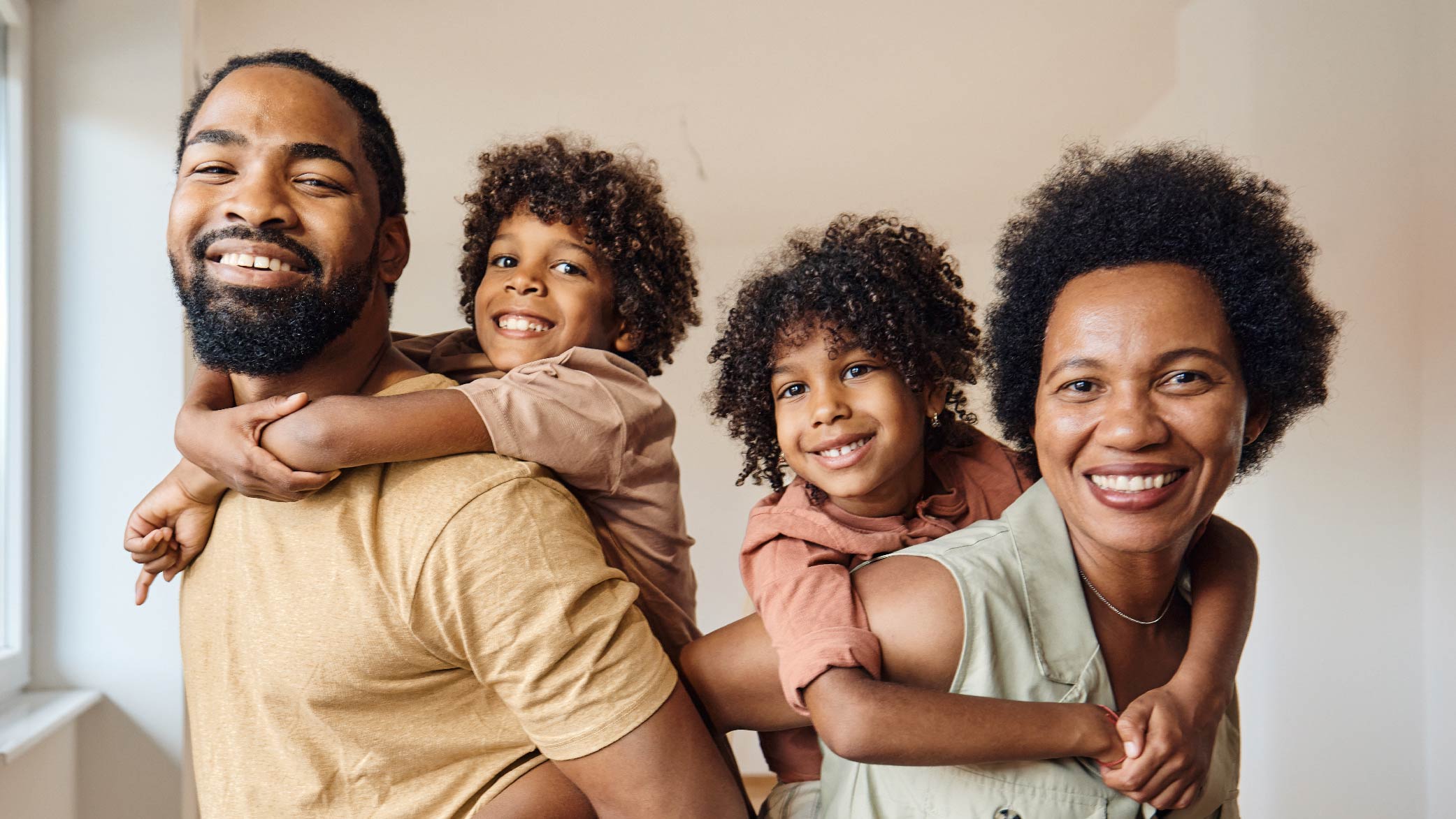 A Black man, woman, and two young children smiling