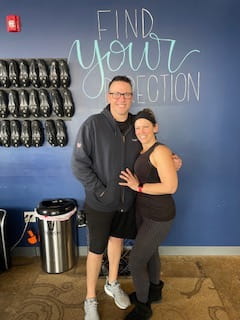 Heather Sommer poses next to a man at a cycling studio